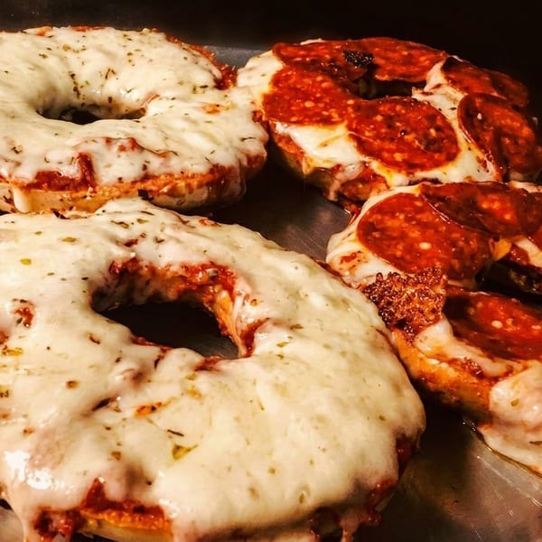 Four pizza bagels, two plain cheese and two pepperoni, on a metal tray.