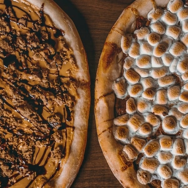 Two dessert pizzas, one with peanut butter and chocolate, the other with toasted marshmallows.